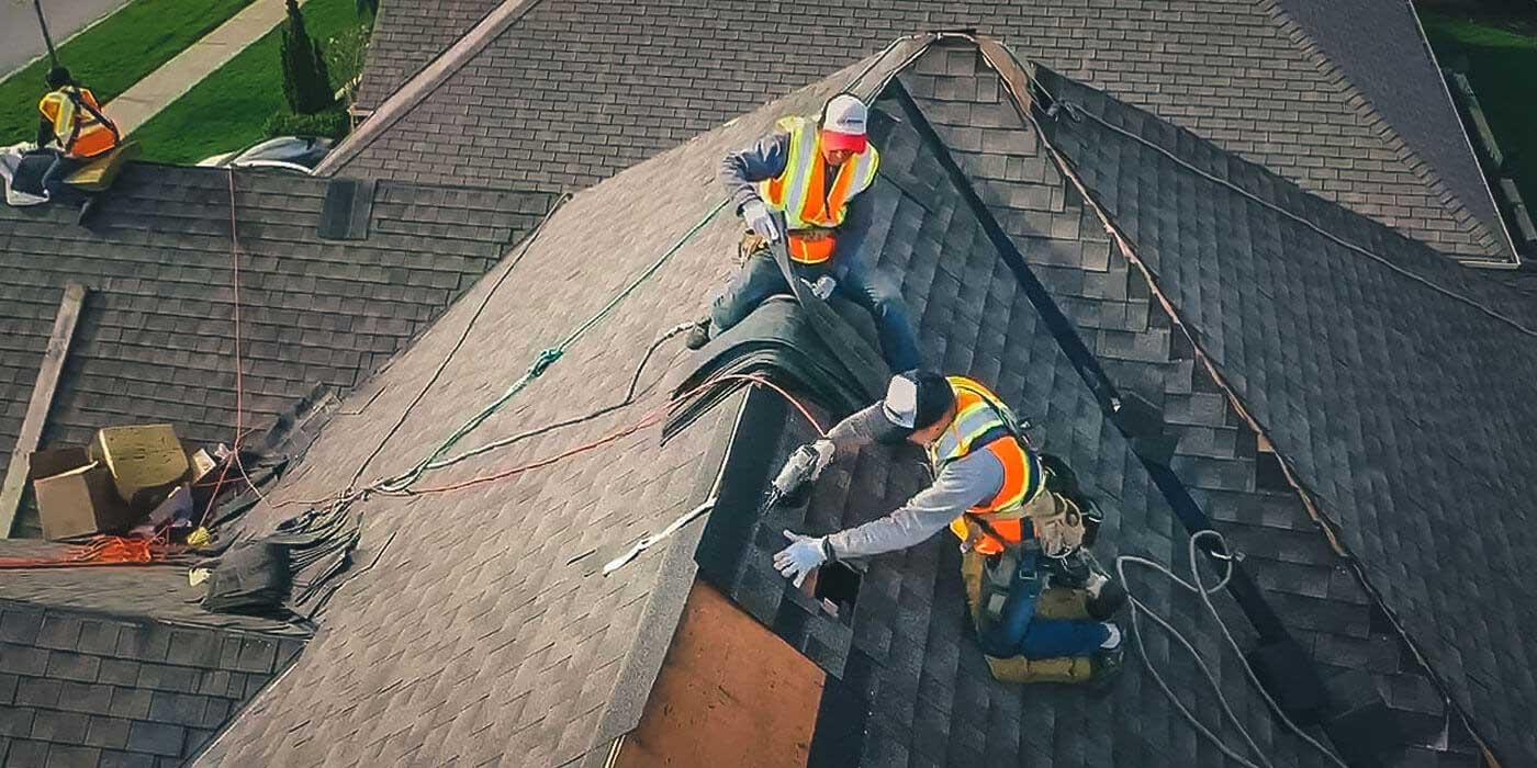 Roofing crew installing shingles on a large residential roof